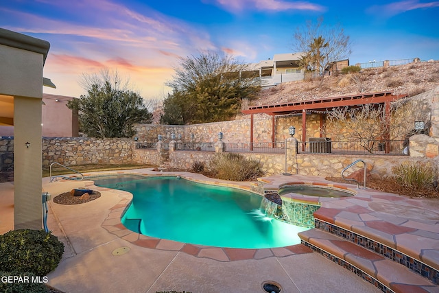 pool at dusk with an in ground hot tub and a patio area