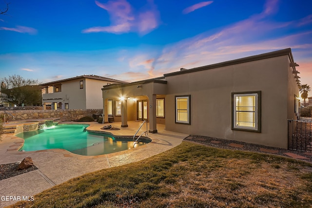 back house at dusk featuring a pool with hot tub, a patio, and a yard