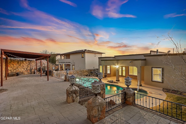 back house at dusk with a patio area and a swimming pool with hot tub