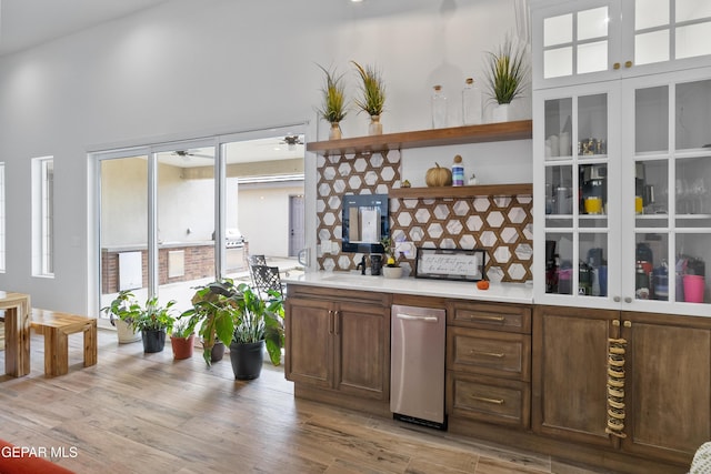 kitchen featuring sink, ceiling fan, a high ceiling, and light hardwood / wood-style floors