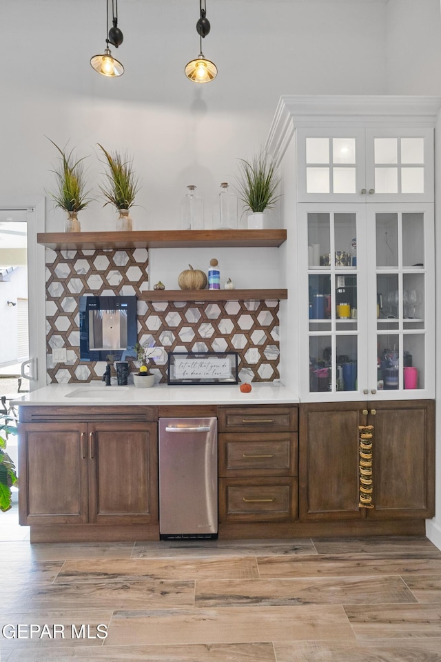 bar featuring sink, decorative light fixtures, and dark brown cabinetry