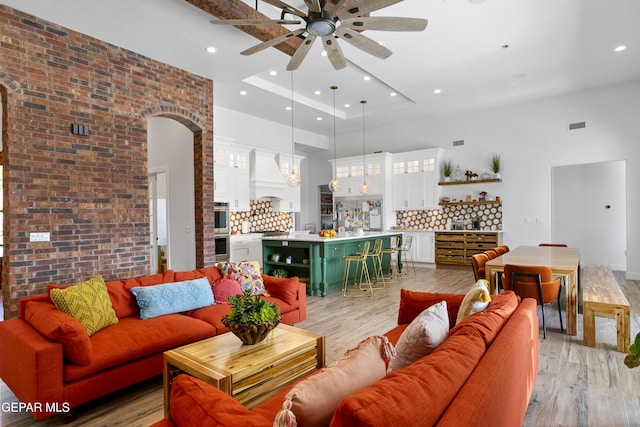 living room featuring ceiling fan, brick wall, and light wood-type flooring