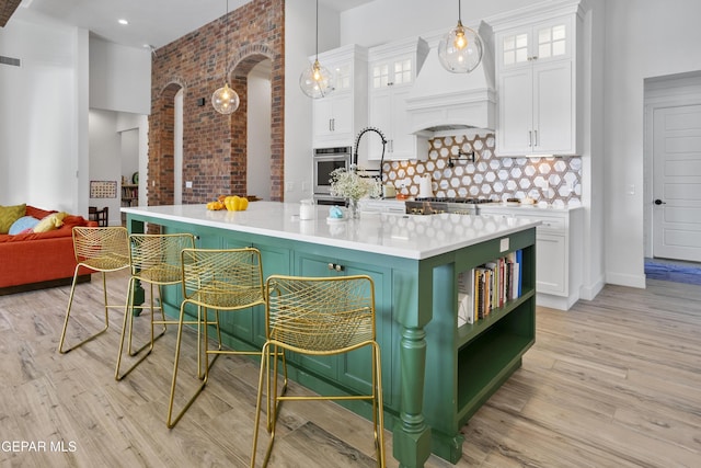 kitchen featuring decorative backsplash, decorative light fixtures, white cabinetry, and custom exhaust hood