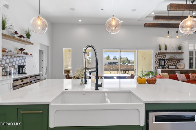 kitchen featuring sink, a high ceiling, hanging light fixtures, and light stone counters