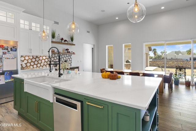 kitchen featuring appliances with stainless steel finishes, white cabinetry, green cabinets, sink, and a center island with sink