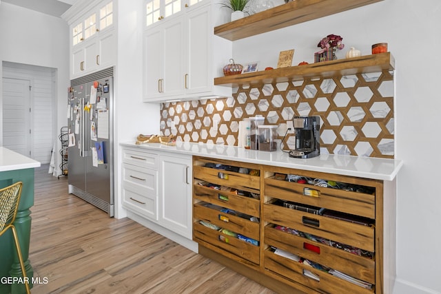 kitchen with built in refrigerator, white cabinetry, and light hardwood / wood-style floors