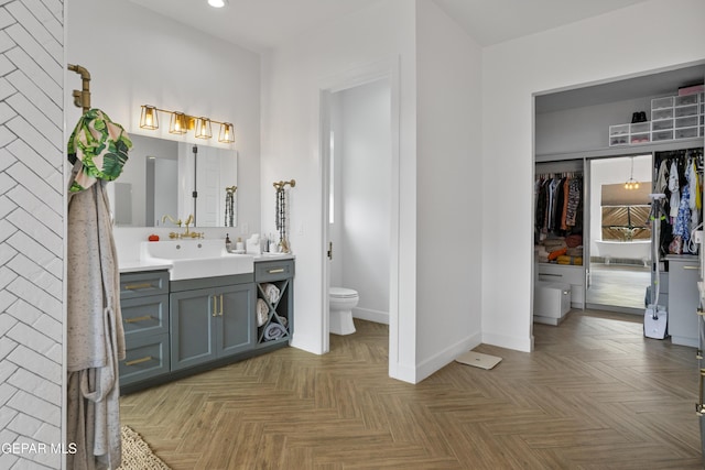 bathroom with parquet flooring, toilet, and vanity