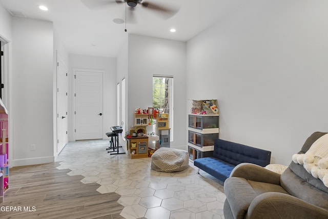 sitting room with ceiling fan and a towering ceiling