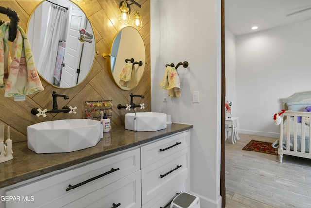 bathroom with wood-type flooring, wood walls, and vanity