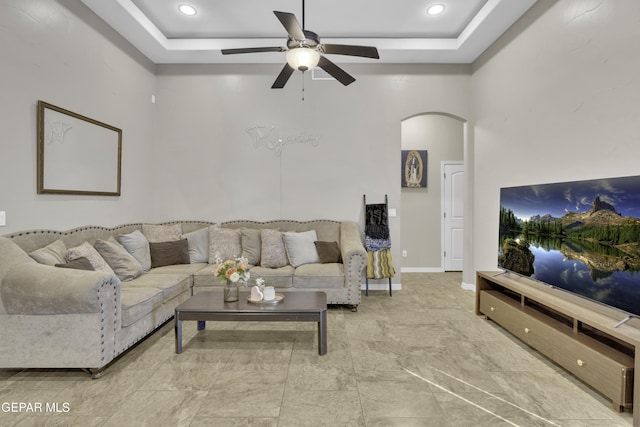 living room featuring ceiling fan and a raised ceiling