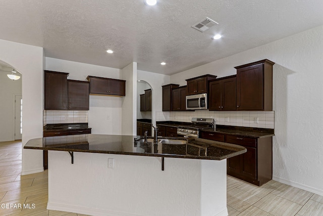 kitchen featuring sink, stainless steel appliances, a kitchen island with sink, and a breakfast bar area