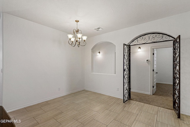 carpeted empty room featuring a notable chandelier