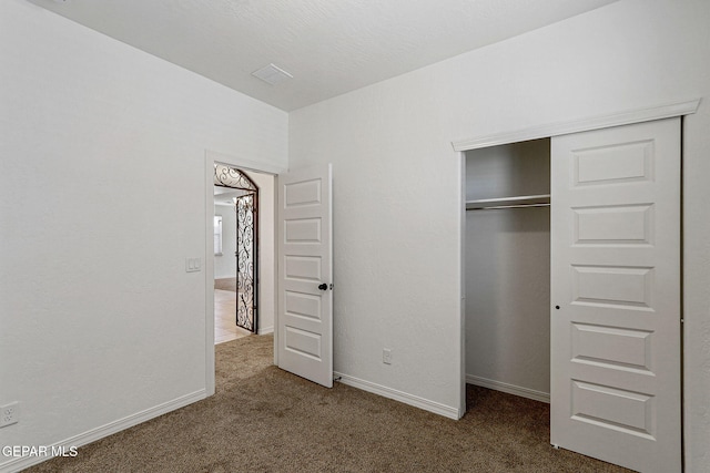 unfurnished bedroom with a closet and dark carpet