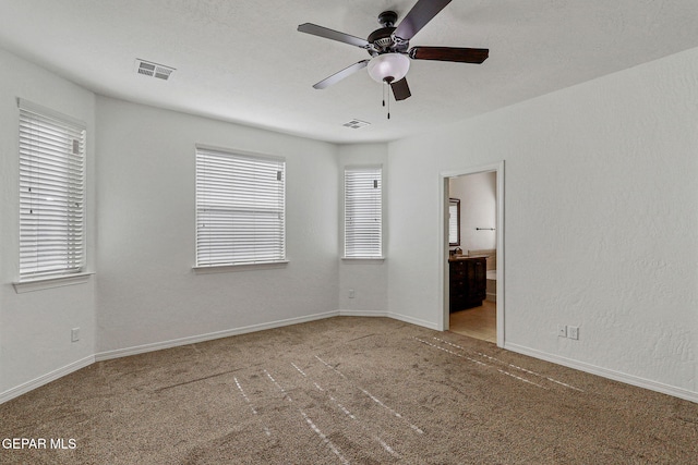 unfurnished bedroom featuring carpet, ensuite bath, and ceiling fan