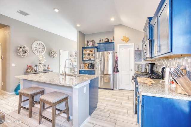 kitchen with blue cabinetry, sink, a center island with sink, appliances with stainless steel finishes, and light stone countertops