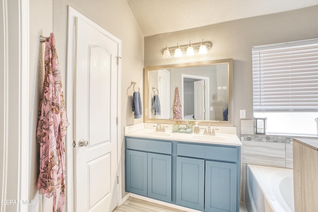 bathroom with vanity, a bath, and vaulted ceiling