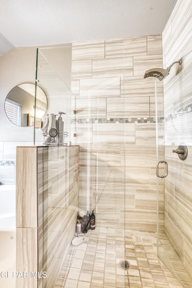 bathroom featuring a shower with door and a textured ceiling