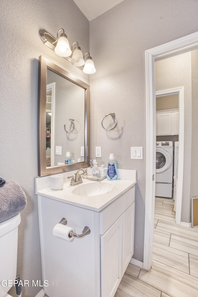 bathroom featuring vanity, toilet, and washer / dryer