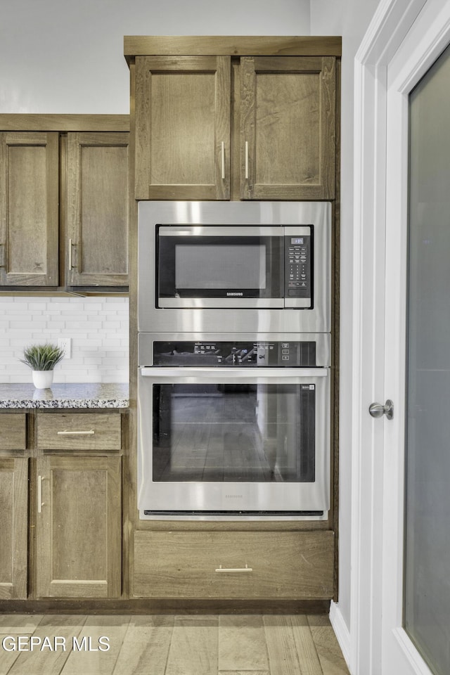 kitchen with light stone counters, decorative backsplash, light tile patterned floors, and appliances with stainless steel finishes