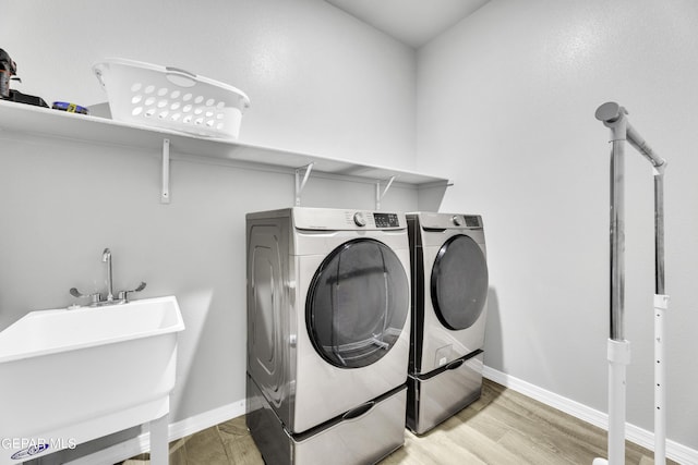 washroom with sink, hardwood / wood-style floors, and washing machine and clothes dryer