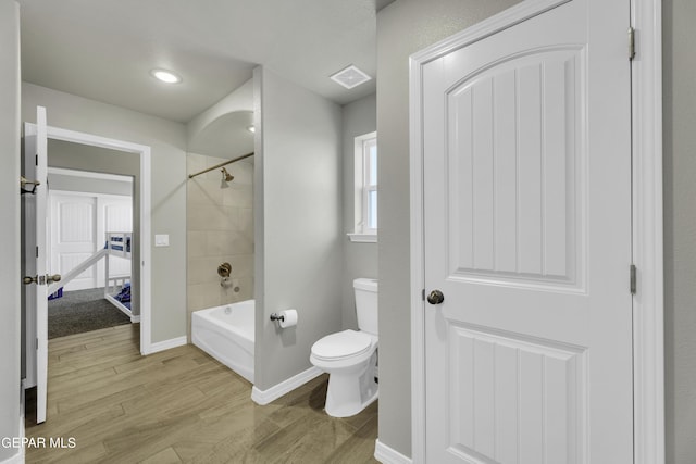 bathroom with toilet, tiled shower / bath, and wood-type flooring