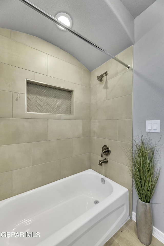 bathroom with wood-type flooring and tiled shower / bath