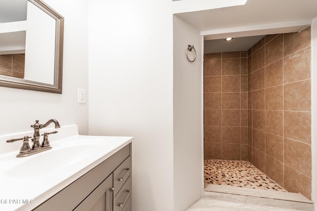 bathroom with a tile shower and vanity