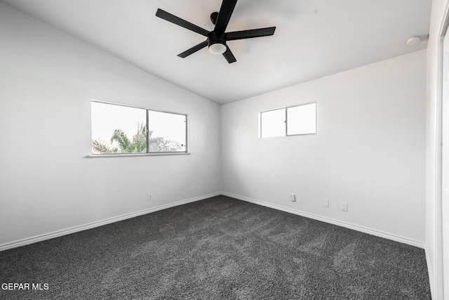 spare room featuring ceiling fan, plenty of natural light, lofted ceiling, and dark colored carpet