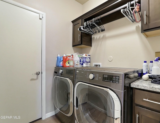 clothes washing area with washing machine and dryer and cabinets