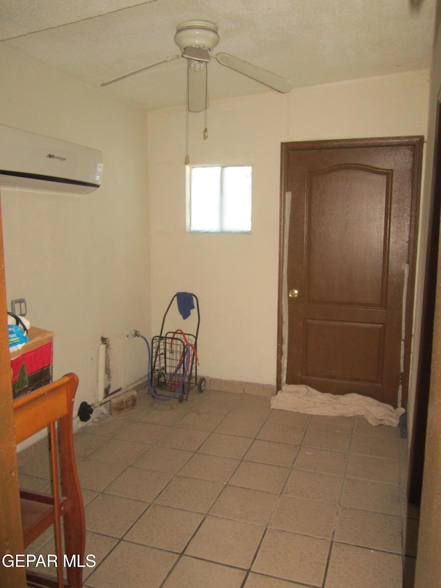 tiled spare room featuring a wall unit AC and ceiling fan