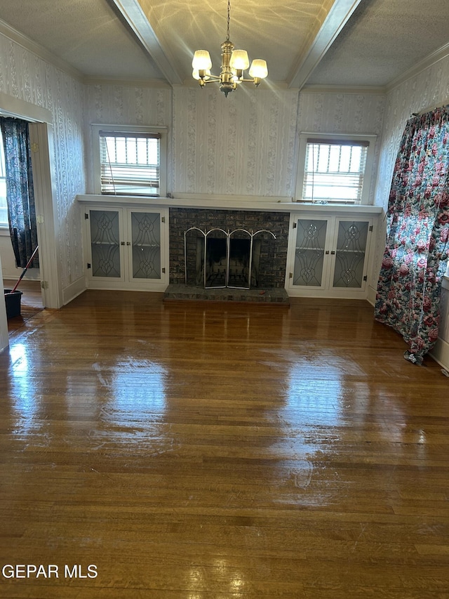 unfurnished living room featuring hardwood / wood-style flooring, a wealth of natural light, a notable chandelier, and a stone fireplace