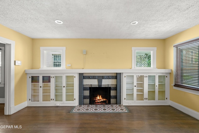 unfurnished living room featuring a tile fireplace, a textured ceiling, and dark hardwood / wood-style flooring