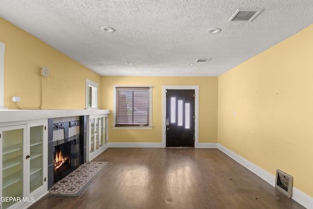 foyer entrance featuring a tile fireplace, wood-type flooring, and a textured ceiling