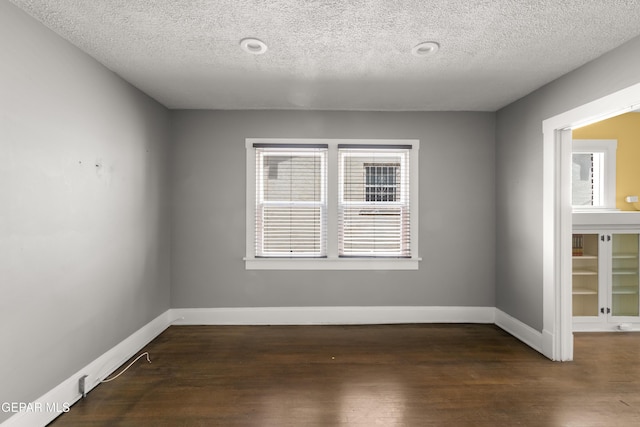 unfurnished room featuring dark hardwood / wood-style flooring and a textured ceiling