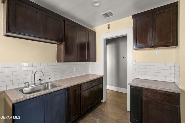 kitchen with dark brown cabinetry, dark hardwood / wood-style floors, sink, and decorative backsplash