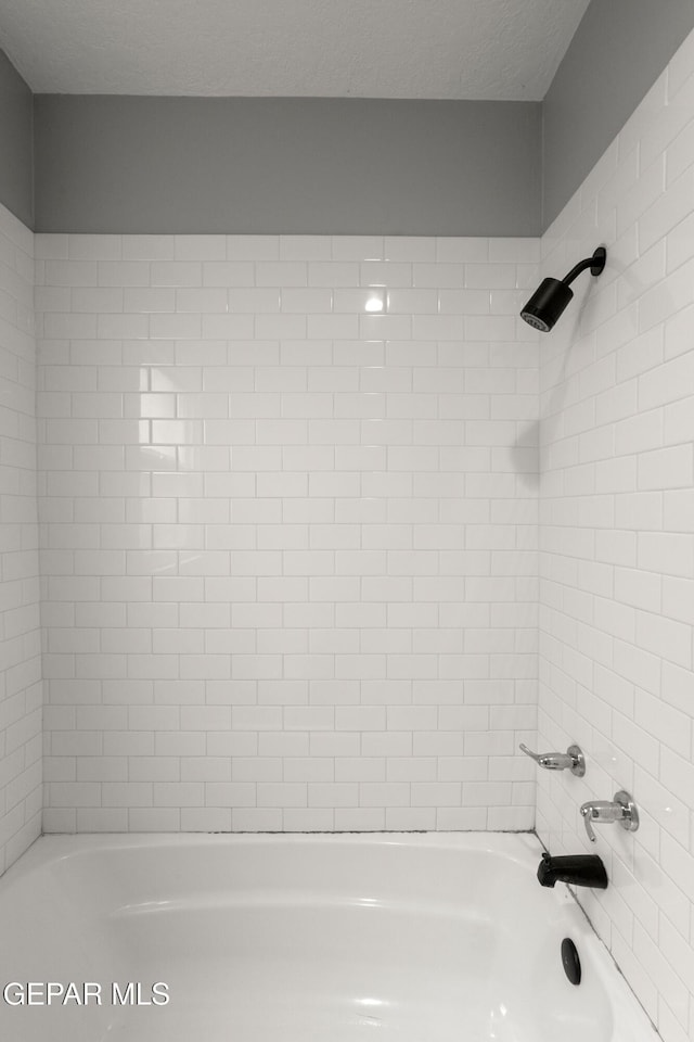 bathroom featuring tiled shower / bath combo and a textured ceiling