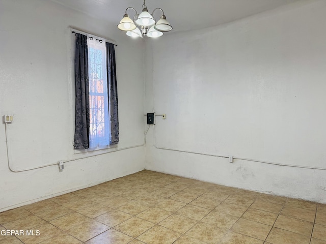 tiled empty room with an inviting chandelier