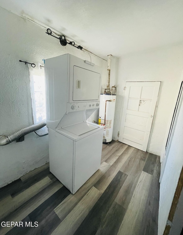 clothes washing area featuring hardwood / wood-style flooring, water heater, and stacked washing maching and dryer