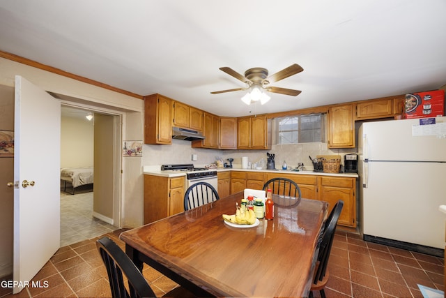 kitchen with decorative backsplash, dark tile patterned floors, ceiling fan, crown molding, and white appliances