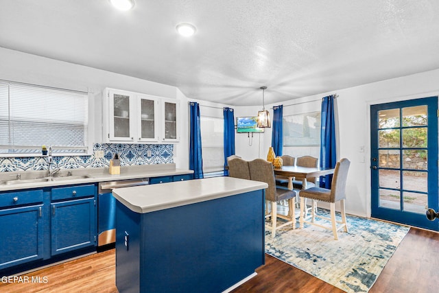 kitchen featuring a center island, blue cabinetry, tasteful backsplash, stainless steel dishwasher, and decorative light fixtures