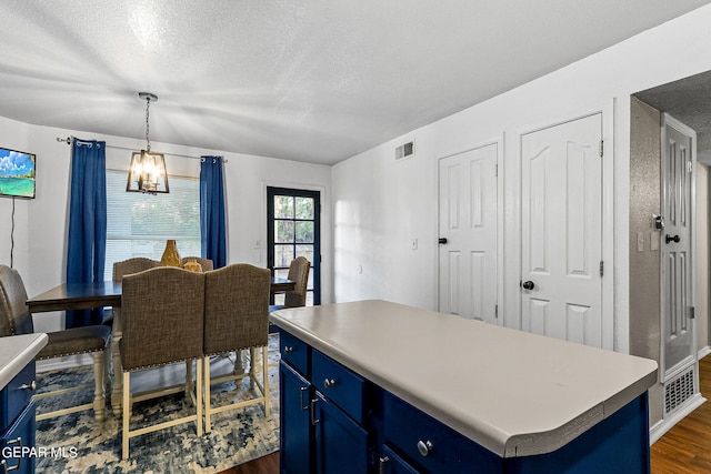 kitchen with a kitchen island, decorative light fixtures, dark hardwood / wood-style floors, and blue cabinets