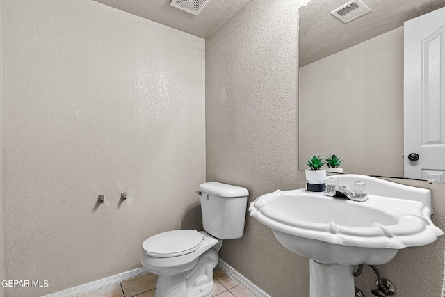 bathroom featuring a textured ceiling, sink, toilet, and tile patterned flooring