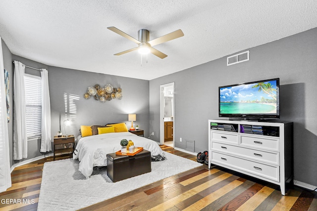 bedroom featuring ceiling fan, a textured ceiling, ensuite bathroom, and dark hardwood / wood-style flooring