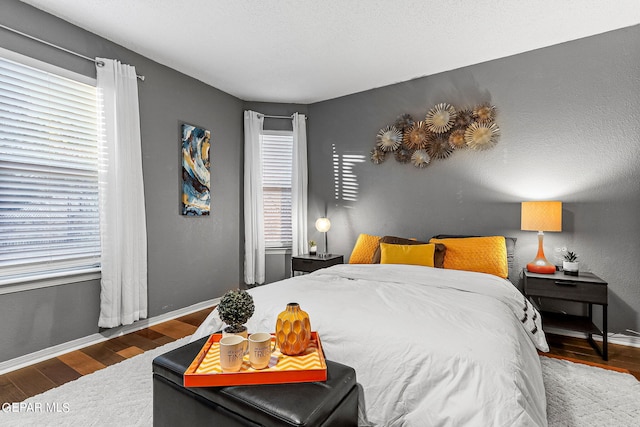 bedroom with dark hardwood / wood-style flooring and multiple windows