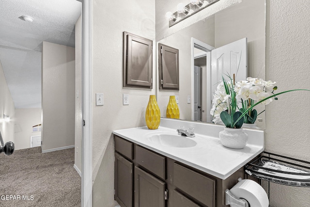 bathroom with vanity, vaulted ceiling, and a textured ceiling