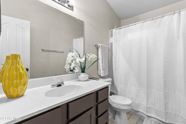 bathroom with toilet, vanity, and tile patterned flooring