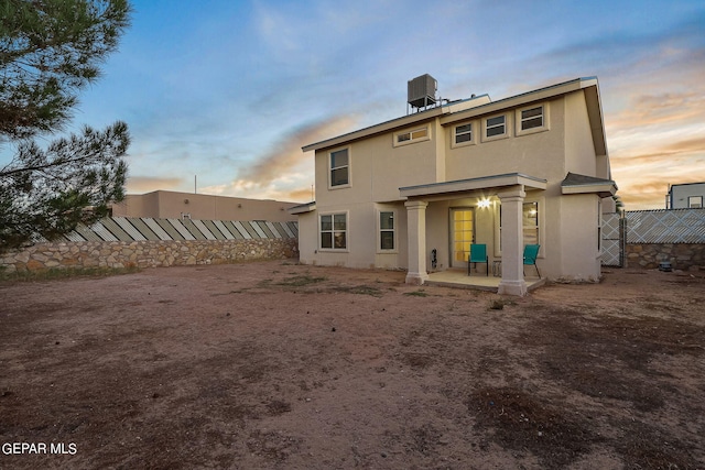 back house at dusk featuring a patio and central AC