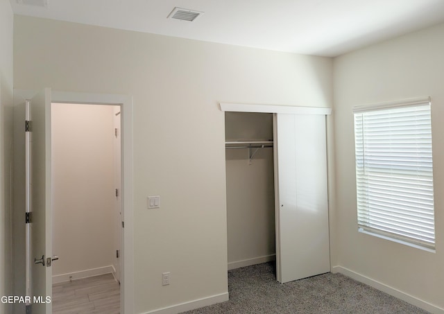 unfurnished bedroom with light colored carpet and a closet