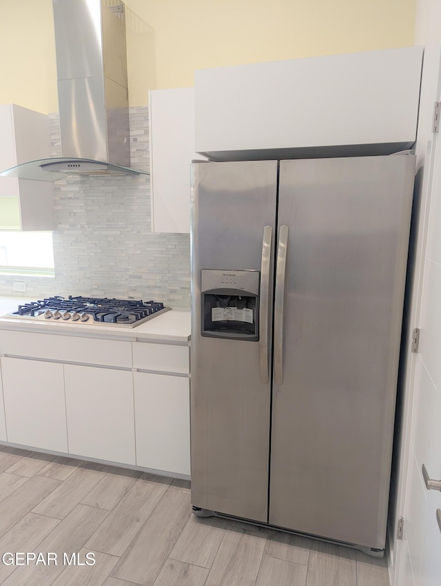 kitchen featuring extractor fan, appliances with stainless steel finishes, white cabinets, and decorative backsplash