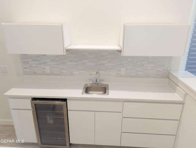 kitchen with white cabinetry, sink, and beverage cooler